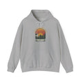 Hoodie with retro 'Backyard Bird Club Est. 2026' badge design featuring a sunset, pine trees and a chickadee at a bird feeder