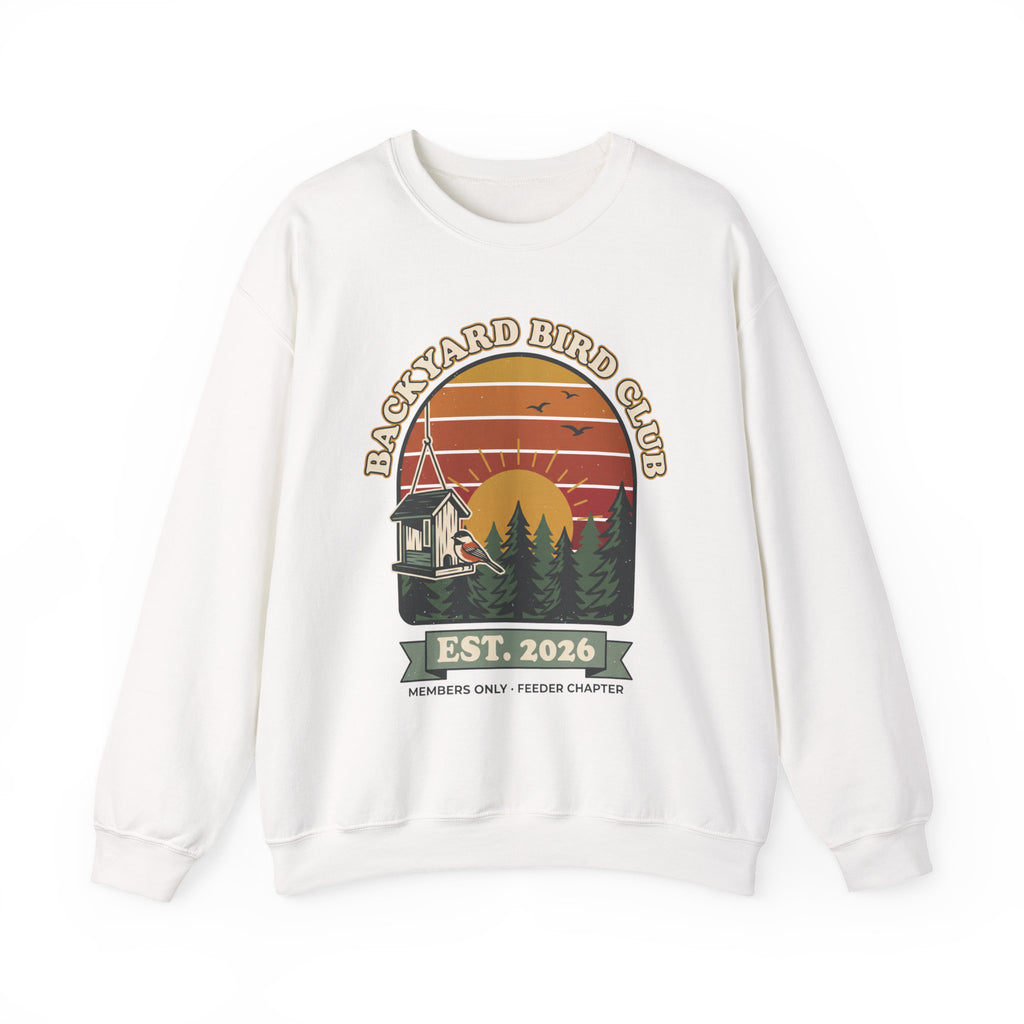 Crewneck sweatshirt with retro 'Backyard Bird Club Est. 2026' badge design featuring a sunset, pine trees and a chickadee at a bird feeder