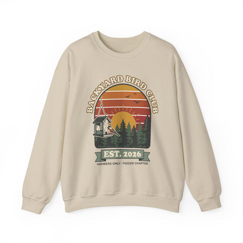Crewneck sweatshirt with retro 'Backyard Bird Club Est. 2026' badge design featuring a sunset, pine trees and a chickadee at a bird feeder